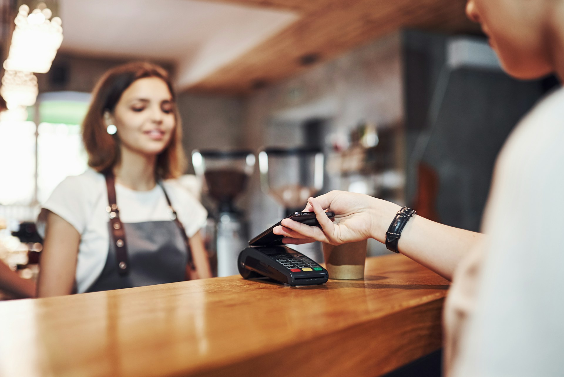 Customer making contactless payment at cafe